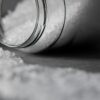 Detailed image of rock salt pouring out from a glass jar with a selective focus effect.